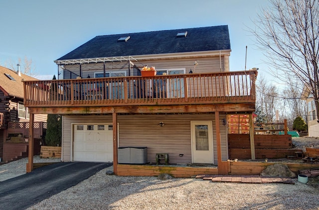 back of house with a garage, a wooden deck, asphalt driveway, and roof with shingles