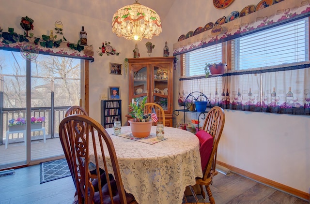dining space with wood finished floors, a chandelier, and baseboards