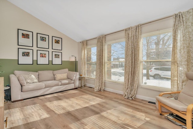 living room with vaulted ceiling, baseboards, wood finished floors, and a healthy amount of sunlight