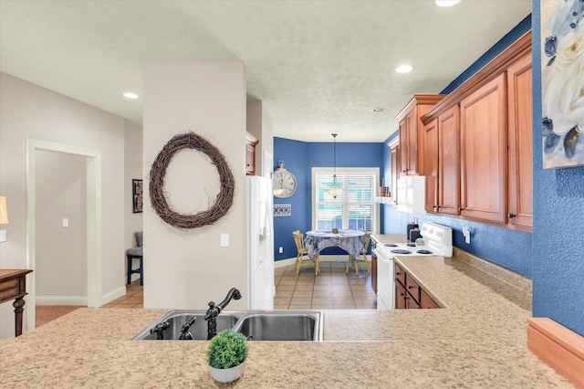 kitchen featuring white appliances, brown cabinetry, a sink, hanging light fixtures, and light countertops