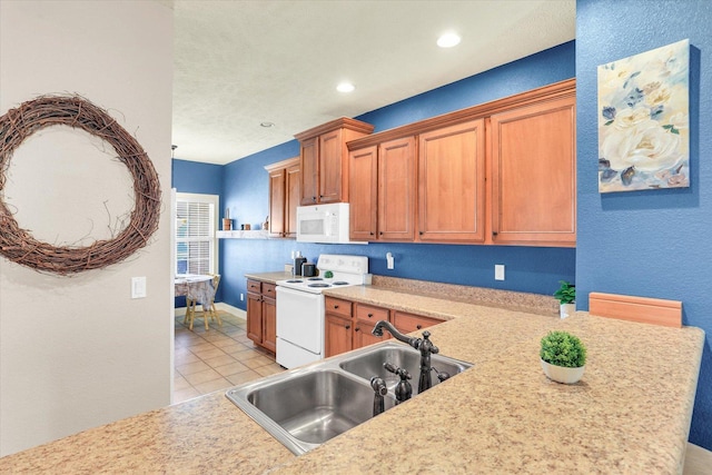 kitchen featuring a sink, white appliances, brown cabinetry, light countertops, and light tile patterned floors