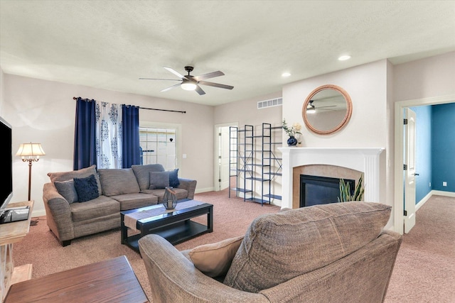 carpeted living area featuring baseboards, visible vents, recessed lighting, ceiling fan, and a glass covered fireplace