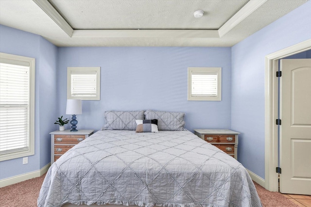 carpeted bedroom featuring a textured ceiling, baseboards, and a tray ceiling