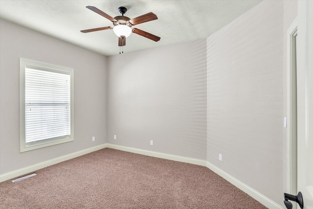 unfurnished room with visible vents, ceiling fan, baseboards, carpet floors, and a textured ceiling