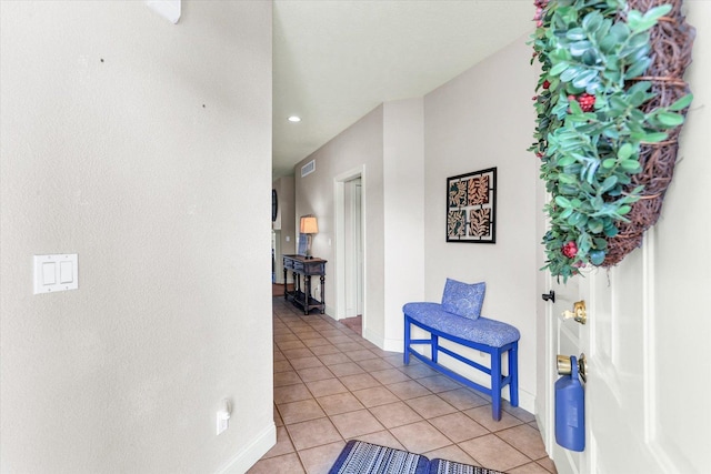 hallway with light tile patterned floors, visible vents, and baseboards