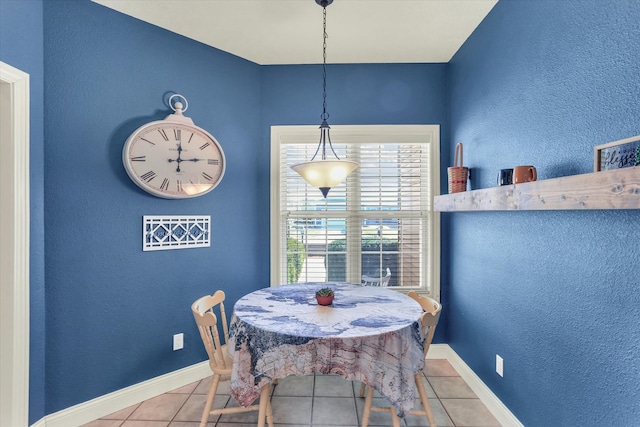 tiled dining room featuring baseboards and a textured wall