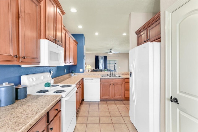 kitchen featuring brown cabinets, a sink, white appliances, light tile patterned flooring, and light countertops