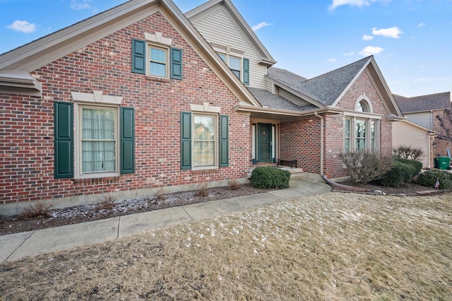 view of front of house featuring brick siding and roof with shingles