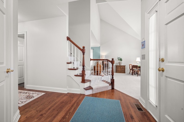 foyer with visible vents, lofted ceiling, wood finished floors, and stairs