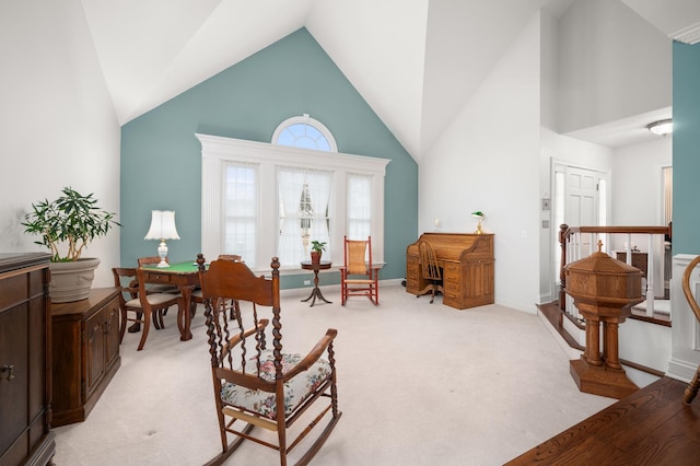 sitting room with light colored carpet, an upstairs landing, high vaulted ceiling, and baseboards