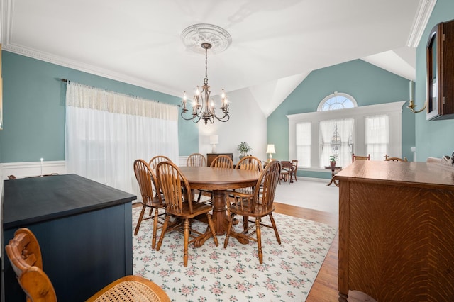 dining area with a chandelier, wood finished floors, and vaulted ceiling