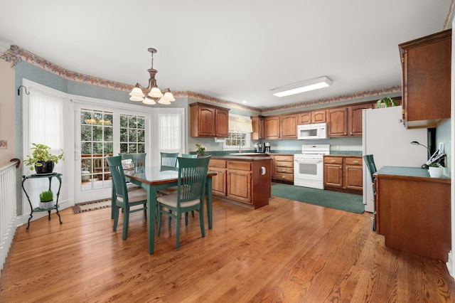 kitchen with white appliances, light wood-style flooring, brown cabinetry, and a sink