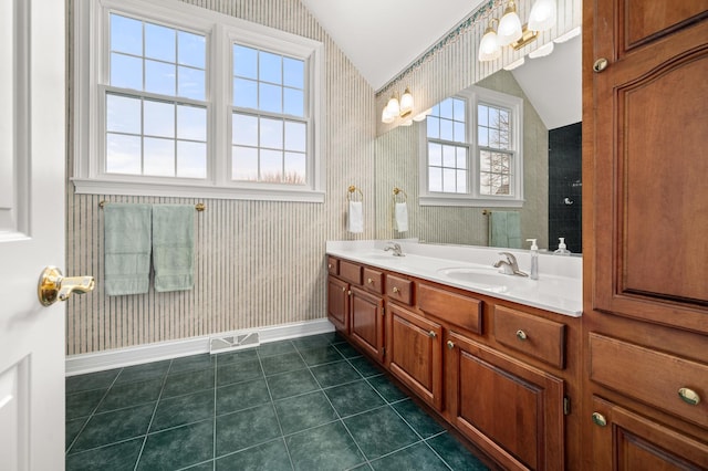 bathroom featuring a sink, lofted ceiling, and wallpapered walls