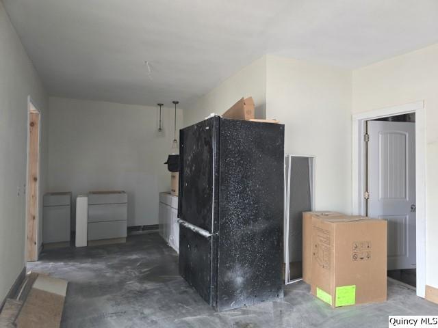 kitchen featuring concrete floors and freestanding refrigerator