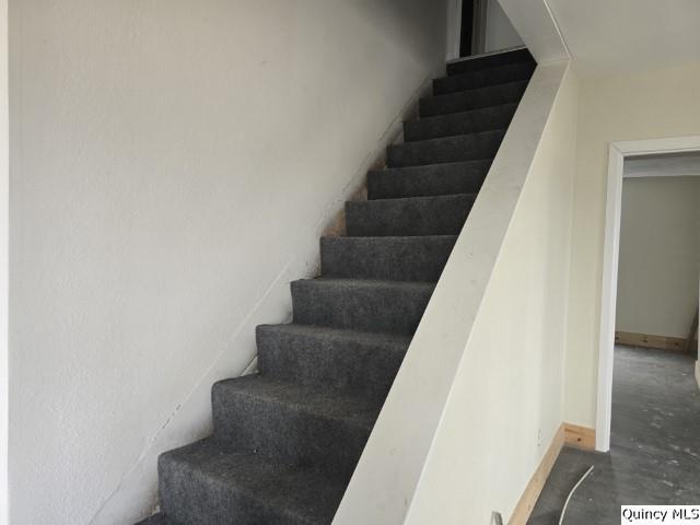 stairs with baseboards and unfinished concrete floors