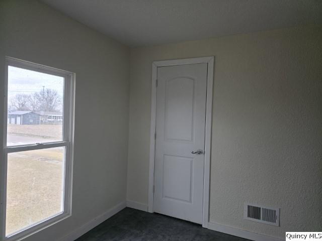 unfurnished room with baseboards, visible vents, and a wealth of natural light