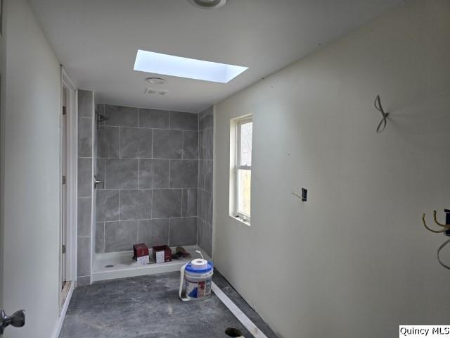 full bath featuring a stall shower, concrete floors, and a skylight