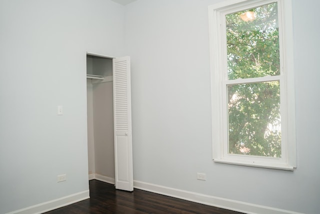 unfurnished bedroom featuring a closet, baseboards, and dark wood-style flooring