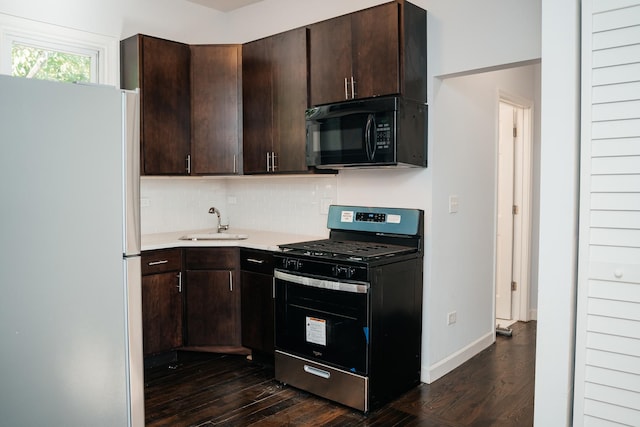 kitchen with dark wood finished floors, freestanding refrigerator, stainless steel range with gas cooktop, black microwave, and a sink