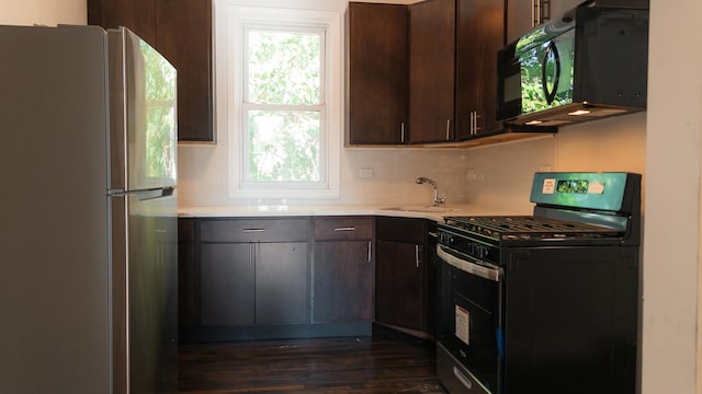 kitchen with light countertops, a sink, black appliances, and dark brown cabinets