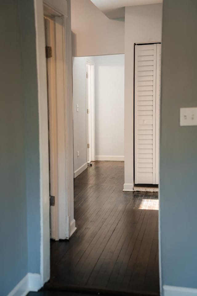 corridor featuring dark wood-style flooring and baseboards