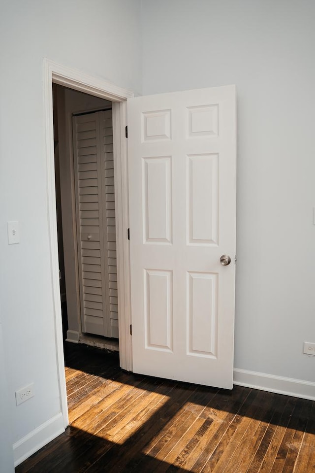 interior space featuring dark wood-type flooring, a closet, and baseboards