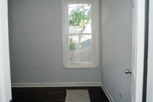 interior space with dark wood-type flooring, visible vents, and baseboards