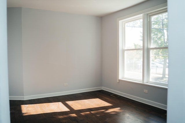 spare room featuring dark wood-style floors, visible vents, and baseboards