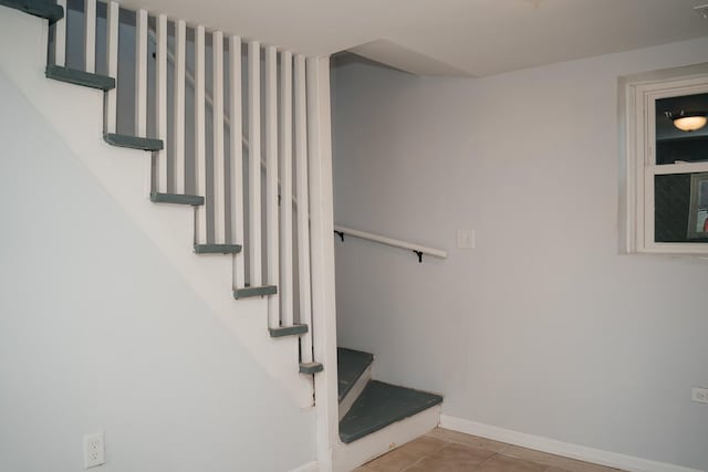 staircase featuring baseboards and tile patterned floors