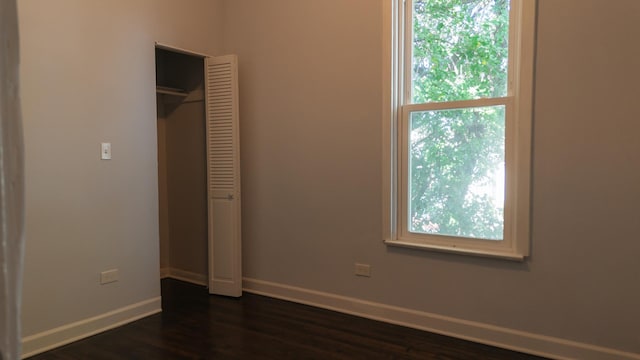 unfurnished bedroom featuring dark wood-type flooring, a closet, and baseboards