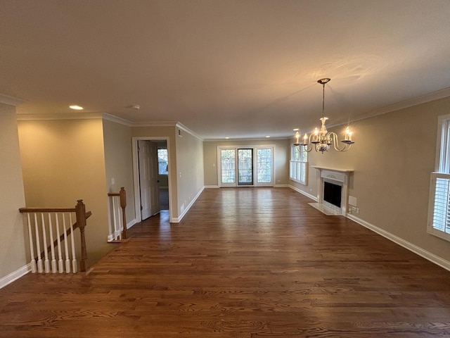 unfurnished living room with ornamental molding, dark wood finished floors, and an inviting chandelier