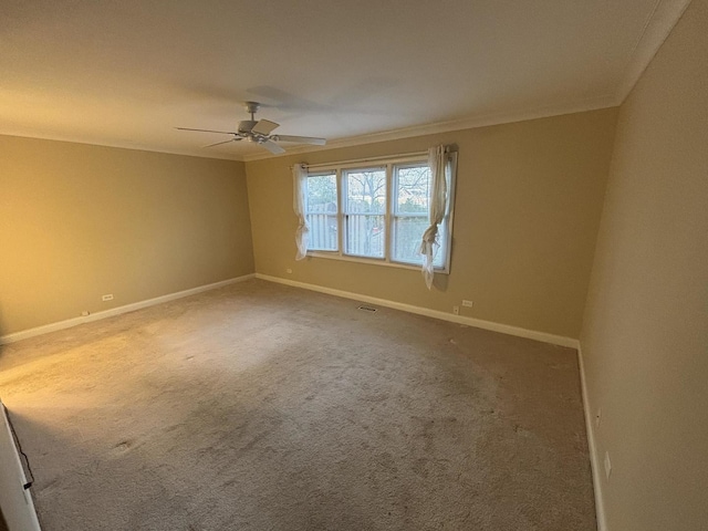 carpeted empty room with crown molding, ceiling fan, and baseboards