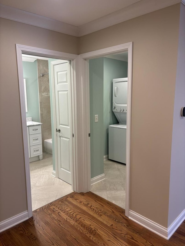 hall with light wood-style floors, stacked washer / dryer, and baseboards