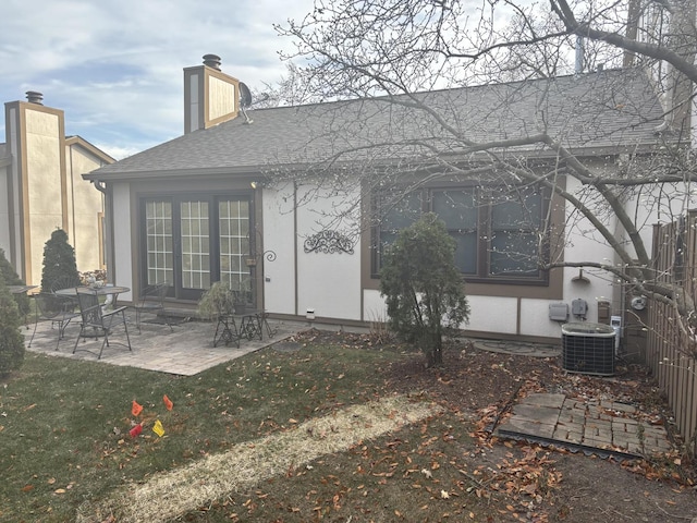 back of property featuring a chimney, stucco siding, a shingled roof, a patio area, and cooling unit