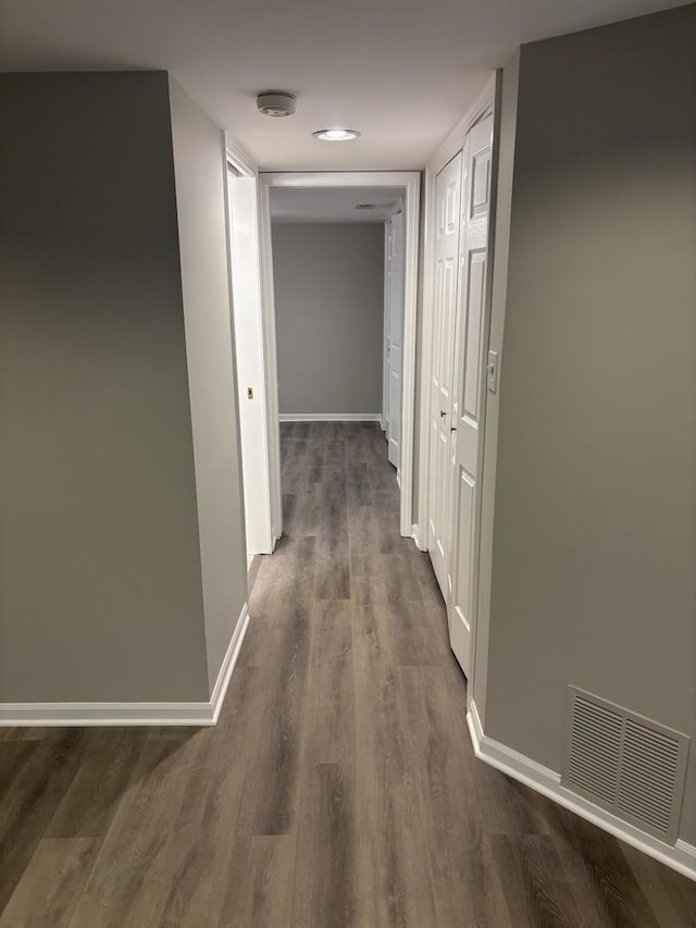 corridor featuring dark wood-style flooring, visible vents, and baseboards