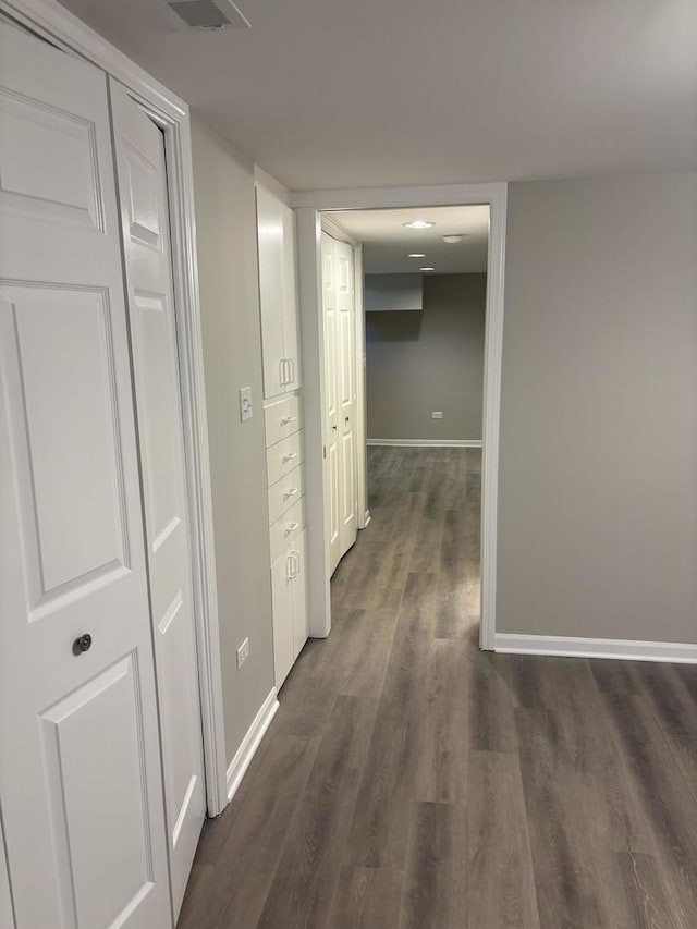 hallway featuring dark wood-type flooring and baseboards