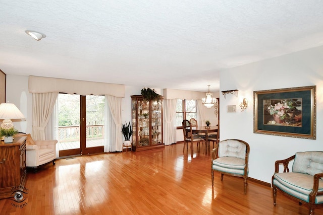 living area with a textured ceiling, baseboards, and wood finished floors