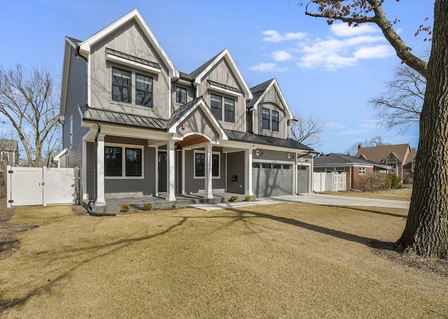 view of front of property featuring driveway, a standing seam roof, a gate, fence, and a garage