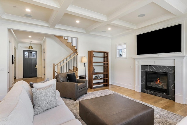 living area with stairway, wood finished floors, beamed ceiling, and coffered ceiling