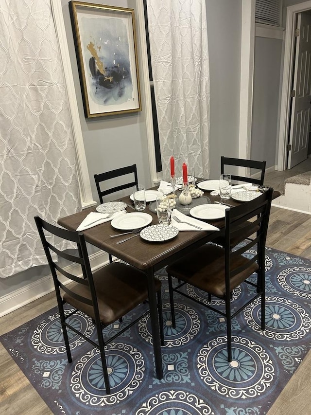 dining space with baseboards and wood finished floors