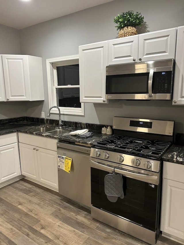 kitchen featuring a sink, stainless steel appliances, light wood-type flooring, and white cabinets