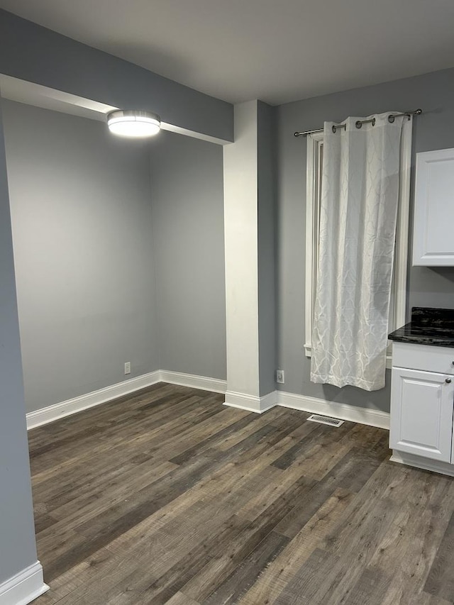 interior space featuring visible vents, baseboards, and dark wood-type flooring