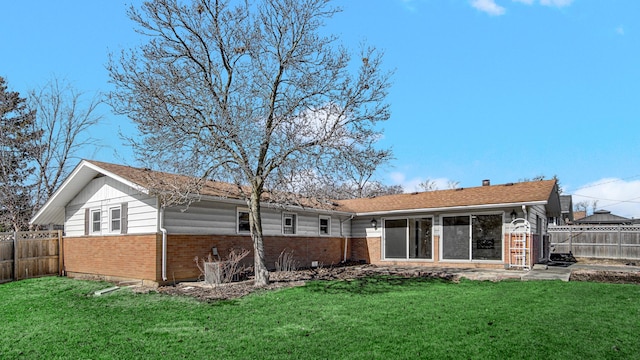 rear view of house with brick siding, a lawn, and a fenced backyard