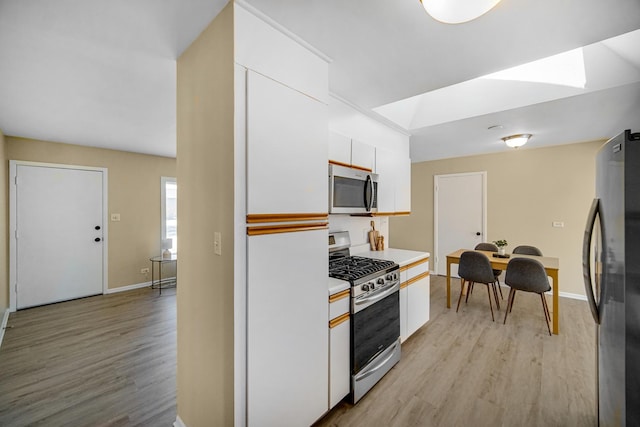 kitchen featuring light wood finished floors, light countertops, appliances with stainless steel finishes, and white cabinets