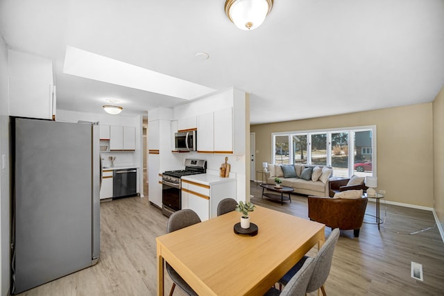 dining area featuring light wood finished floors, visible vents, and baseboards