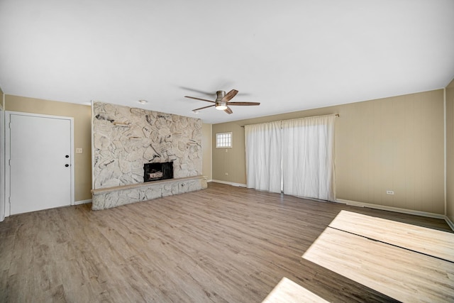 unfurnished living room featuring ceiling fan, a fireplace, wood finished floors, and baseboards