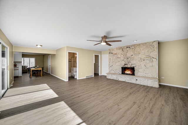 unfurnished living room featuring ceiling fan, a fireplace, wood finished floors, and baseboards