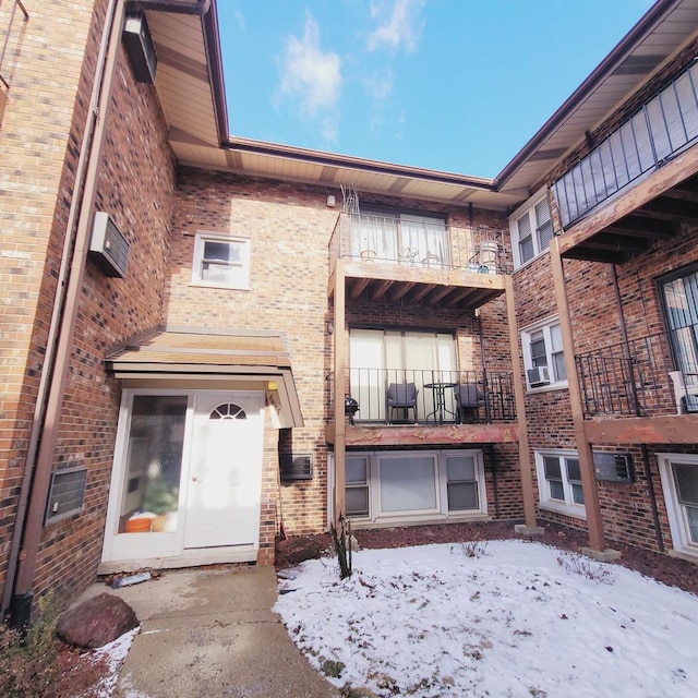 snow covered property with brick siding