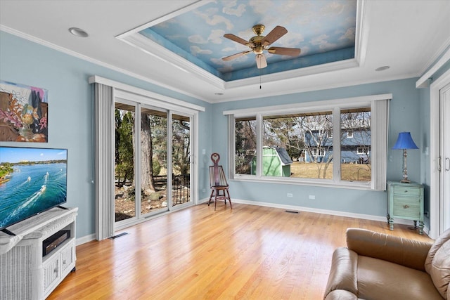 sitting room with a tray ceiling, light wood-style floors, ceiling fan, and crown molding