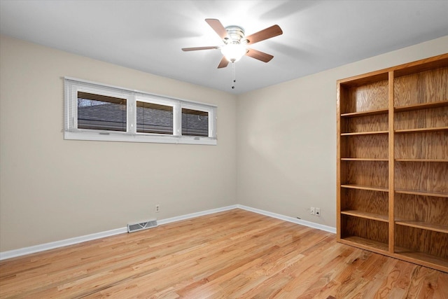 spare room with light wood-style flooring, a ceiling fan, visible vents, and baseboards